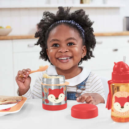 Little Girls Smiling eating on her Skip Hop food container