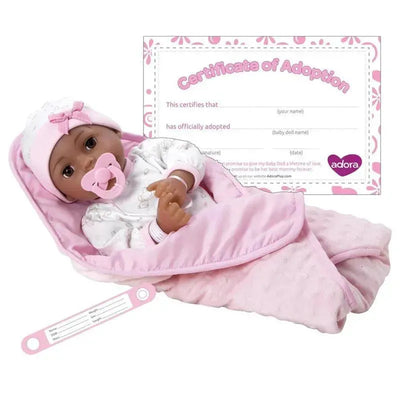 Adora Adoption Baby Joy is a doll bundled in a pink blanket, with a pacifier, accompanied by a pink adoption certificate.