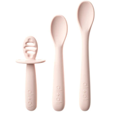 Three blush-colored baby spoons are displayed, including one with a textured handle for easy grip and two varying sizes for different stages of feeding.