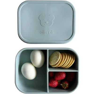 Leakproof silicone bento box in Dream Blue, featuring two eggs, strawberries, and crackers in divided sections.