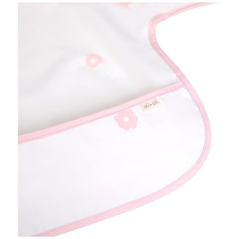 Long sleeve smock bib in pink with floral patterns, featuring a stitched label from Ali + Oli.