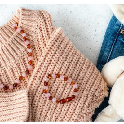 Amber Stone Baltic Amber & Rose Quartz Bracelet with pink and amber beads displayed on a knitted pink sweater.