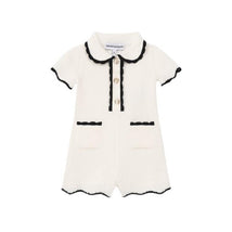 White collared romper for baby girls featuring black trim, button closure, and two front pockets.