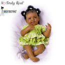 Alexis Baby Doll by Ashton Drake, featuring a smiling baby doll in a green dress with a flower detail.