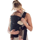 A woman holds a baby in the Babybjorn Baby Carrier Mini 3D Mesh in black, showcasing comfort and convenience.