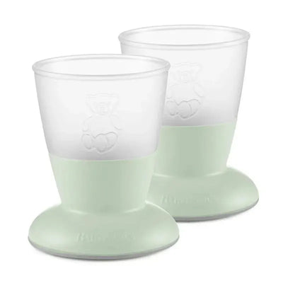 Two Babybjorn baby cups in powder green, designed for easy handling with a non-slip base and featuring a bear design.