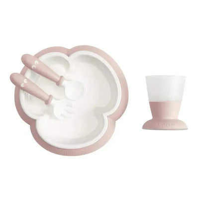 BabyBjorn Baby Feeding Set in powder pink, including a divided plate, two utensils (fork and spoon), and a cup.