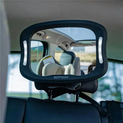 Bbluv Ezimoov baby car mirror with LED light, mounted on the back seat, reflecting a car interior and child seat.