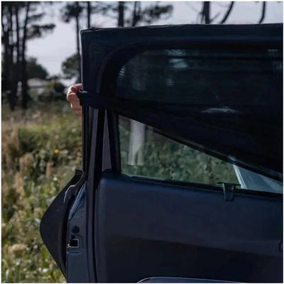 Car door with a person holding a black sun shade sock, designed to block sunlight for passengers.