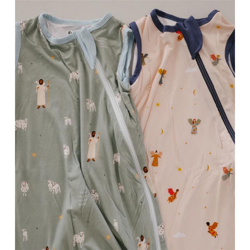 Two baby sleep sacks, one green with cow prints and one light pink with angel illustrations, both featuring zippers.