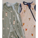 Two baby sleep sacks, one green with cow prints and one light pink with angel illustrations, both featuring zippers.