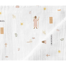 Muslin swaddle blanket featuring illustrations of Jesus, sheep, sun, and various symbols in soft colors.