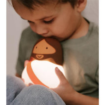 Child holds a glowing Jesus-shaped night light, gently kissing it, with a soft, comforting ambiance.