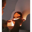 Child placing hands on a glowing night light shaped like Jesus, enhancing a cozy atmosphere in a bedroom.