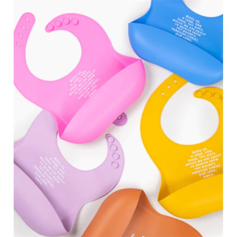 Silicone bibs in various colors, including rose pink, with text featuring a blessing prayer, designed for mealtime use.