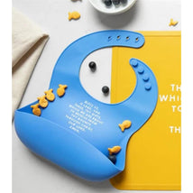 Silicone bib in sage green featuring a prayer text and small fish-shaped snacks, set on a bright yellow background.