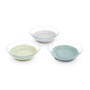 Three glass plates in grey, green, and light green, designed for serving food, stacked with a sleek, modern look.