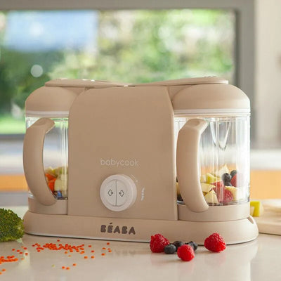 Beaba Babycook Duo in Oat color with two transparent bowls, featuring fruits, vegetables, and a control knob.