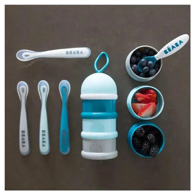 Four silicone spoons and a stackable food container for babies, featuring various fruits, in blue and white colors.