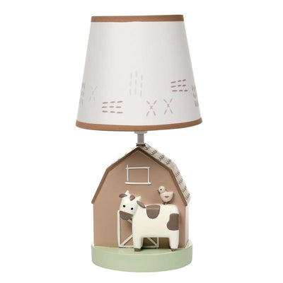 Decorative nursery lamp featuring a barn base with a cow and bird figurine, topped with a patterned shade.