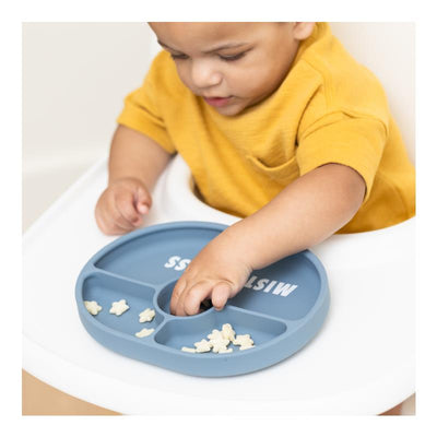 A child in a yellow shirt using a Bella Tunno Mister Mess Wonder Plate, featuring sections for food.