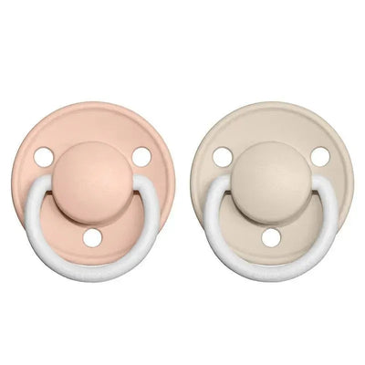 BIBS 2Pk De Lux pacifiers in Blush Night and Vanilla Night colors, featuring soft silicone nipples and round shields.