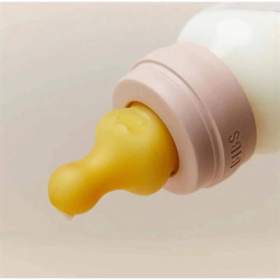 Latex bottle nipple in yellow attached to a light-colored bottle with a pink collar.