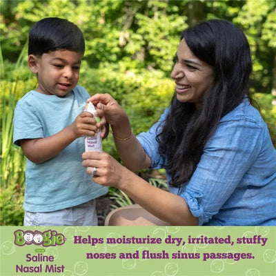 A woman helps a young boy hold a bottle of Boogie Wipes Saline Nasal Mist, which moisturizes and clears nasal passages.