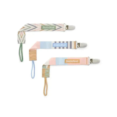 Three Booginhead pacifier clips in geometric pink patterns, featuring secure clips and colorful designs.