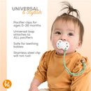 Sage green BooginHead pacifier clip securely attaches a white pacifier to a baby wearing a rust-colored shirt, promoting safety and style.