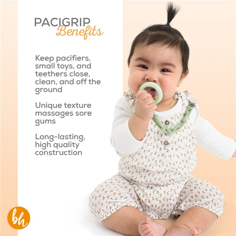 Baby chewing on a sage green pacifier attached to a BooginHead silicone chain, wearing a flower-patterned outfit.