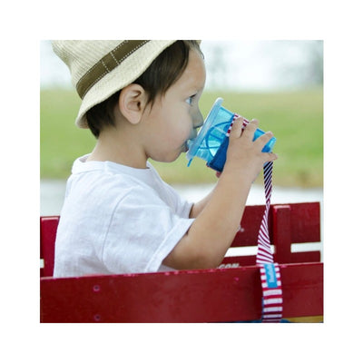 Child in a straw hat sipping from a blue BooginHead SippiGrip cup with nautical red stripe, seated in a red wagon.