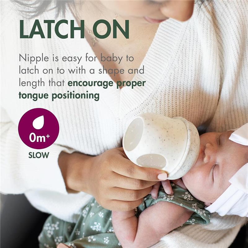 Boon 4 oz Nursh silicone baby bottle in green speckle, being held by a parent while feeding a baby, with text highlighting its easy latching design.