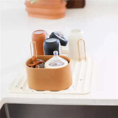 Silicone baby bottle drying rack in Boho Beige holding baby bottles and accessories on a beige drying mat.