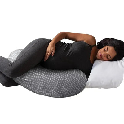 Pregnant woman relaxing on a Boppy Cuddle Pregnancy Pillow with a gray basket weave pattern, supporting her body comfortably.