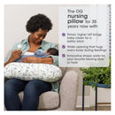 Boppy Nursing Pillow in beige foliage design, supporting a woman feeding a baby with a bottle.