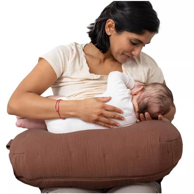Boppy Nursing Pillow Luxe in Chestnut Muslin supports a mother as she breastfeeds her baby comfortably.