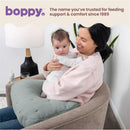 Boppy Nursing Pillow Luxe in sea green, used by a smiling woman holding a baby, with a cozy indoor setting.