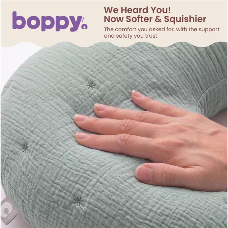 Boppy Nursing Pillow Luxe in sea green muslin, with a hand resting on its soft, textured surface.
