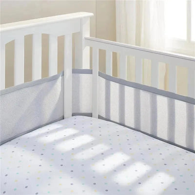 Gray BreathableBaby mesh crib liner fitted in a white crib, featuring a dotted mattress and soft sunlight.