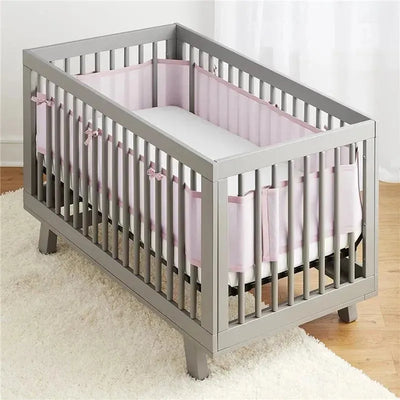 Classic BreathableBaby mesh crib liner in light pink, installed in a gray crib with a soft white mattress.