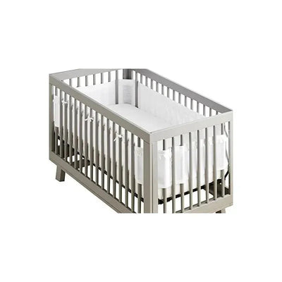 Deluxe Breathable Mesh Crib Liner in white ruffle, fitted inside a wooden crib with slatted sides.