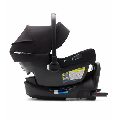 Bugaboo Turtle Air by Nuna car seat with a reclined position and black fabric, featuring safety labels and fastening mechanisms.