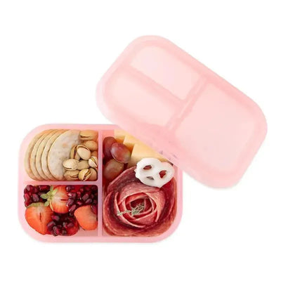 Bumkins pink snack/lunch bento box with three compartments containing fruit, cheese, salami, crackers, and nuts.
