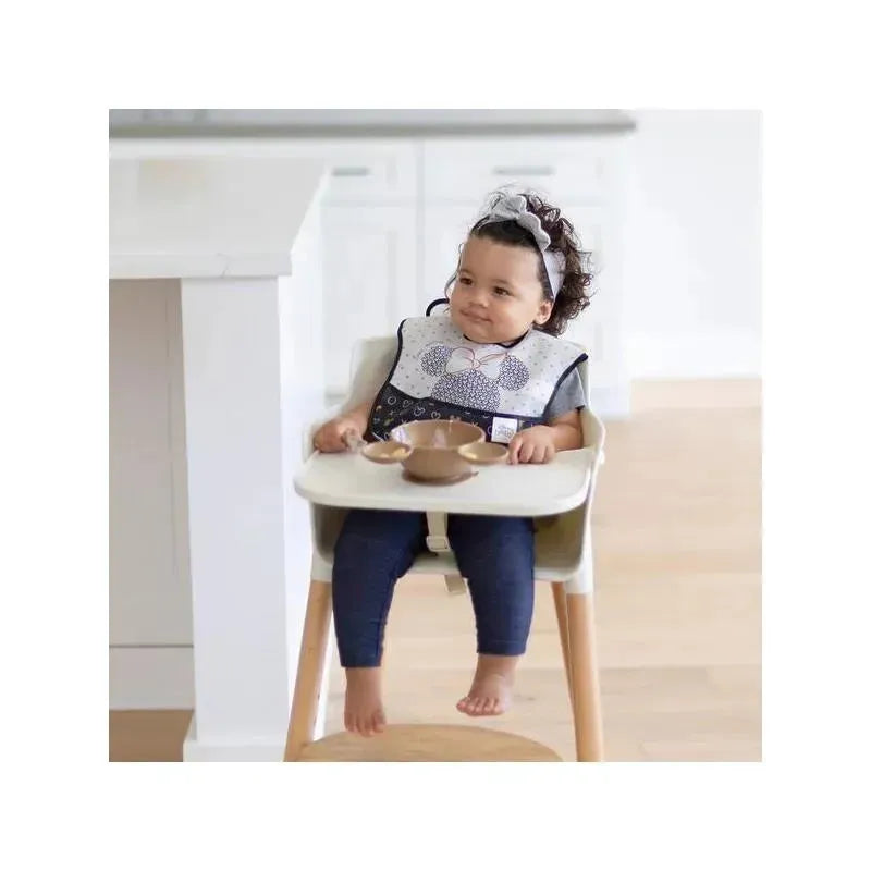 Toddler seated in a high chair wearing a Mickey Mouse bib, with a brown silicone feeding set on the tray.