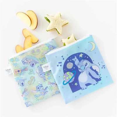 Large Snack Bags from Bumkins feature colorful Stitch designs, surrounded by sliced apples and star-shaped food items.