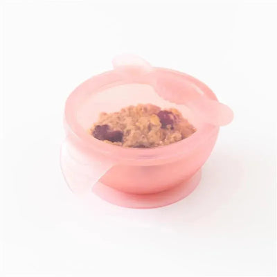 Bumkins pink silicone baby feeding bowl with a suction base, containing a textured food mixture.