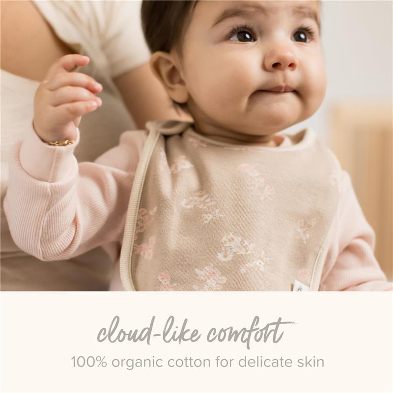 Baby wearing a beige floral bib made from 100% organic cotton, promoting comfort for delicate skin.