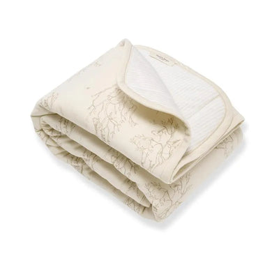 Reversible cream blanket with a subtle tree branch pattern, folded with soft texture and striped backing.