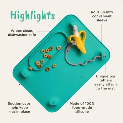 Silicone baby mat in spearmint with suction cups, toy tethers, and Cheerios scattered on it, highlighting ease of cleaning.